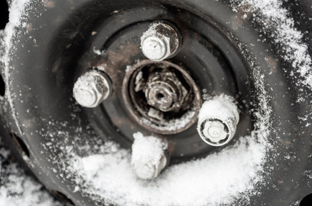 car wheel covered and covered with snow, winter driving, icy conditions, studded tires for winter,...