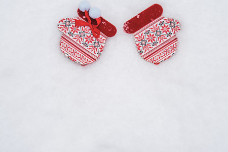 winter holiday background with toy mittens on a background of snowy weather and snow, close-upの写真素材