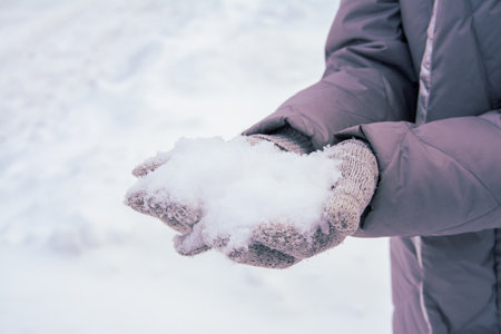 fluffy snow in the cold winter in gloved hands, swirling snow and snowfall, winter weather, close-upの写真素材