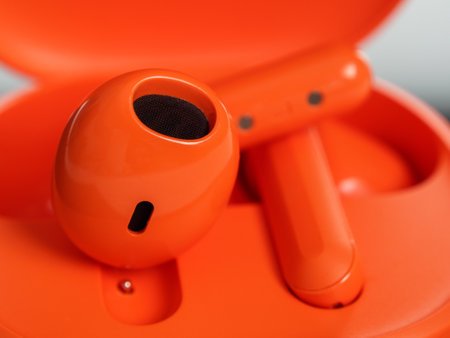 Close-up of bright orange wireless headphones. The headphones stand out with their stylish and...