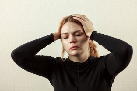 Girl with a headache: close-up, the girl holds her temples, her facial expression conveys discomfort...