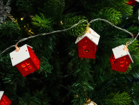 A Christmas garland in the form of houses, sparkling with lights on the tree, creates a cozy atmosphere and a magical holiday mood.の写真素材