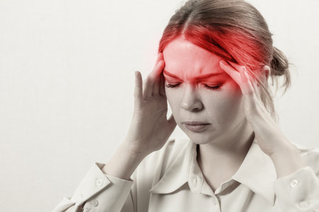 A girl suffers from a migraine: close-up, holding her head, eyes closed, expression of pain and discomfort.の写真素材