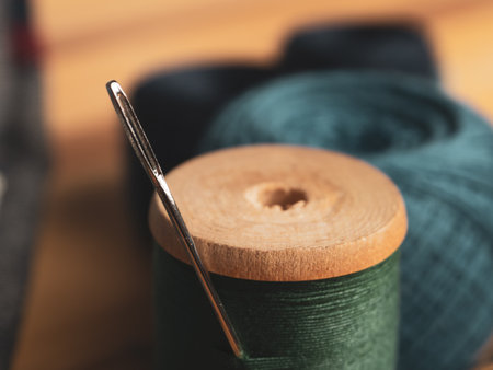Close-up of a threaded needle and measuring tape against a background of fabrics, symbolizing the art of sewing and needlework.の写真素材