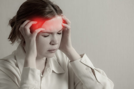 A girl suffers from a migraine: close-up, holding her head, eyes closed, expression of pain and discomfort.の写真素材