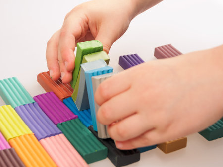 The child holds bright plastic clay in his hands, demonstrating the soft texture and rich colors of the material.の写真素材