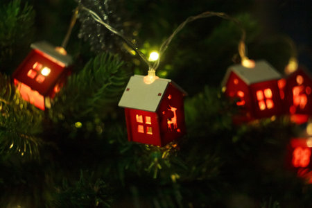 A Christmas garland in the form of houses, sparkling with lights on the tree, creates a cozy...