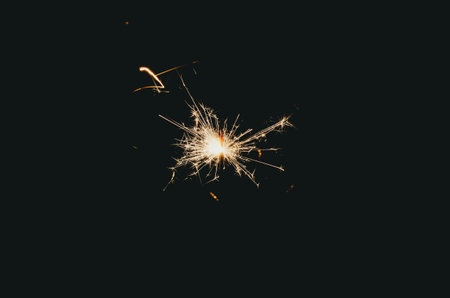 Sparklers sparkle brightly against a black background, creating the effect of magic and celebration, filling the atmosphere with joy.の写真素材