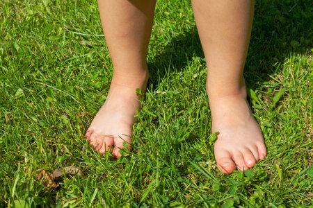 A baby's bare feet on green grass, capturing the innocence and joy of childhood discovery in nature on a warm day.の写真素材