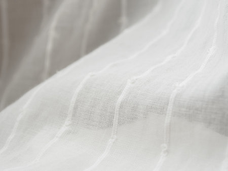 A close-up of a light translucent fabric that plays with the sun's rays, creating a feeling of...