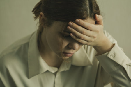 A girl suffers from a migraine: close-up, holding her head, eyes closed, expression of pain and discomfort.の写真素材