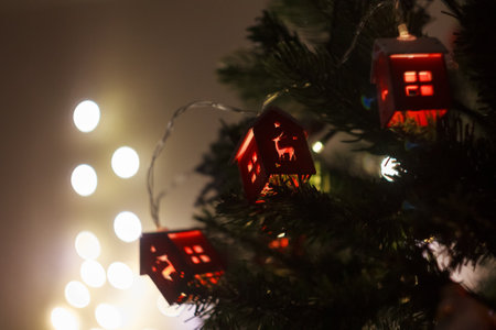 A Christmas garland in the form of houses, sparkling with lights on the tree, creates a cozy atmosphere and a magical holiday mood.の写真素材