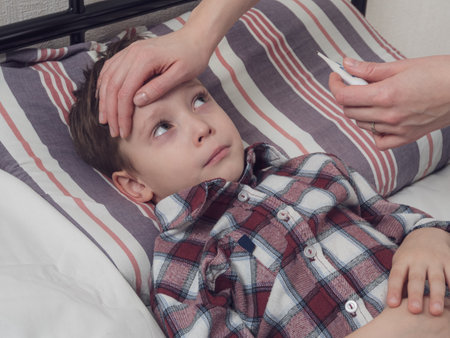 A mother measures the temperature of a sick child, carefully supporting him at the time of illness.