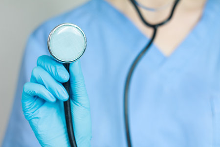 Doctor with stethoscope in hand conducting examination, providing quality patient care, close-up.の写真素材