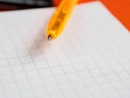 A close-up shot of a pen resting on a notepad, with ample free space in the background.