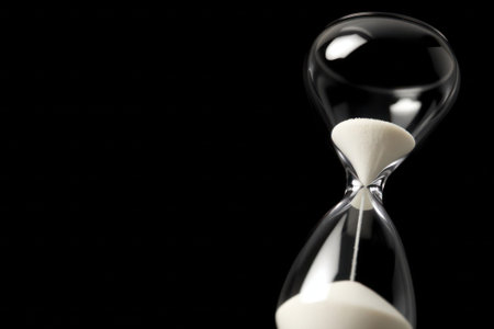 Hourglass close-up, black background. Time, deadline and concept of passing time. With copy space.の素材