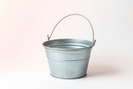 A solitary galvanized metal bucket sits on a plain white surface.の素材