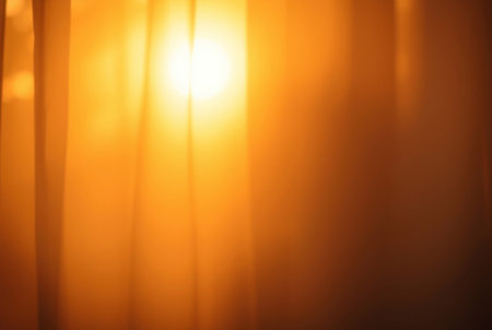 Abstract golden light streaming through sheer curtains at dusk.の素材