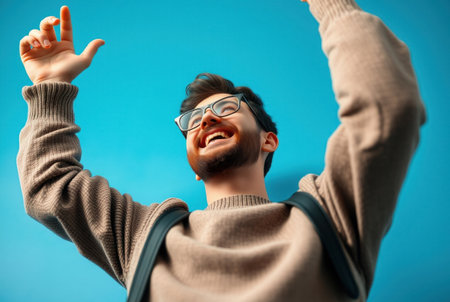 A young man joyfully raises his arms towards the blue sky.の素材