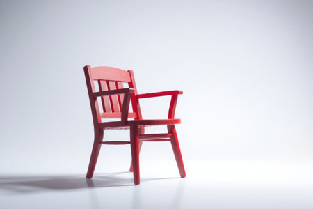 A solitary red wooden chair sits starkly against a white background.の素材