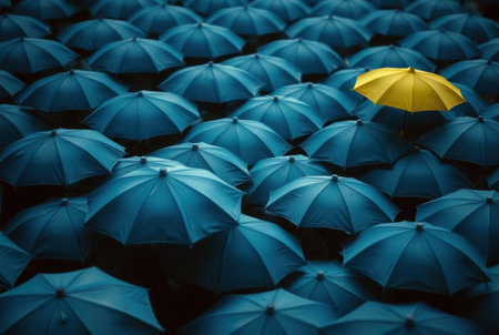 A solitary yellow umbrella amidst a vast array of blue umbrellas.の素材