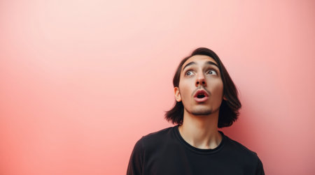 Portrait of a surprised young man on a pink background. Copy space.の素材