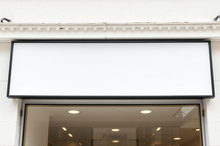 A blank storefront window with a black frame and lighting, showing architectural design.の素材