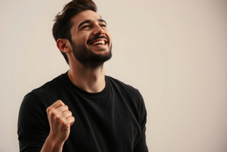 A young man with a joyful expression reaches upwards with excitement.の素材