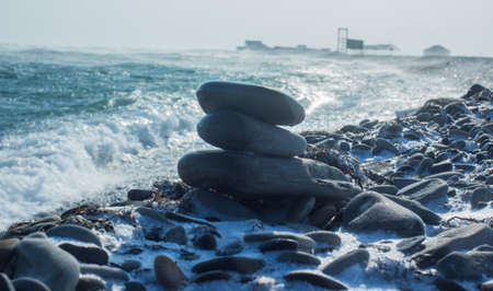 rocky, snow-covered sea beach with stormy sea wavesの写真素材