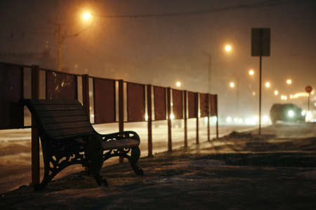 Bench stands near the roadway at night.の写真素材