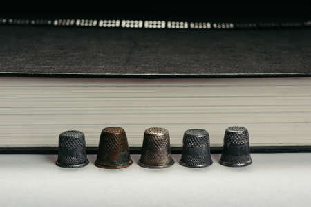 Several old ones in a row of arranged thimbles on the background of the pages of the book.の写真素材