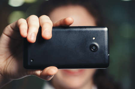A caucasian woman holding a phone closes her eyes. Black phone. Business.の写真素材