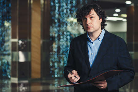 Business man with a folder in his hands in the office. Classic business. Carrying out of consultations.の写真素材