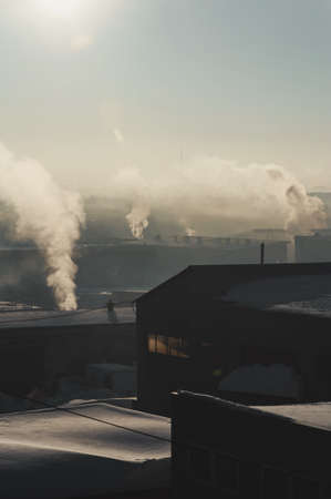 Industrial buildings in the fog on the blue sky backgrond. Warehouses. Smoke from the pipe. Smog.の写真素材