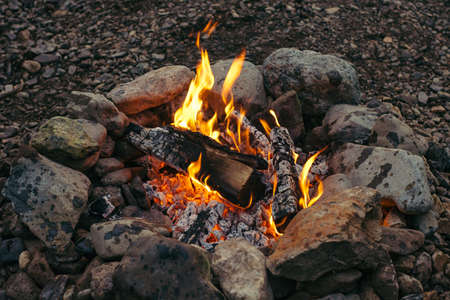 Evening small fire made of birch logs ennobled with stones. Warm hearth.の写真素材