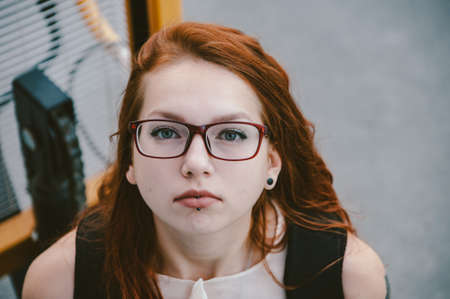 Portrait of a red-haired girl in red glasses.の写真素材