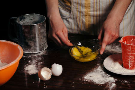 A woman is beating eggs in a bowl. Cooking pie, biscuit, liver.の写真素材