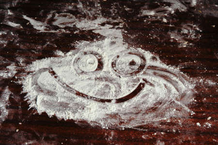 The smile face is drawn by the flour scattered on the table.の写真素材