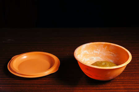 An orange cup with a dough stands alone on a wooden table on a black background.の写真素材