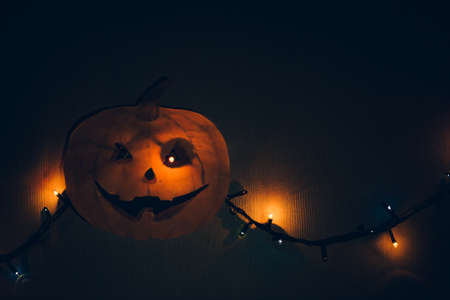 A paper pumpkin with a flashing garland in place of the eyes, hanging on the wall. A horrible template for Halloween.の写真素材