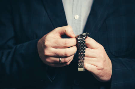 A business man in a suit sets up time in a wristwatch.