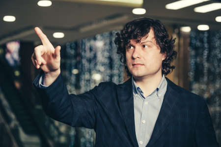 Curly man working with a virtual touchpad on the screen. Business man interacts with the holographic...