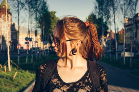 Beautiful young girl with red hair. The hair is gathered in a ponytail. Red hair, dyed with henna. Summer sunny day.の写真素材