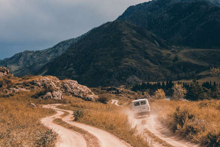 The car is moving forward along a dirt road among the mountains and hills. Mountain Altai.の写真素材