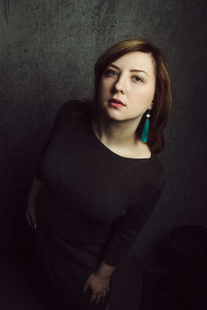 Vintage portrait of beautiful stylish girl with turquoise earrings on gray studio background.の写真素材