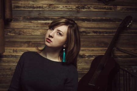 Vintage portrait of beautiful stylish girl with turquoise earrings in old wooden hut.の写真素材