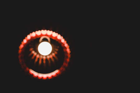 Abstract image of glowing chandelier with red ornament in dark room on black background with copy...