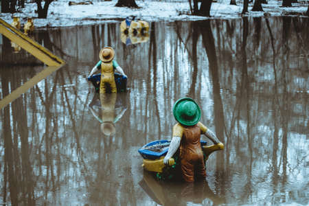 Figurines in form of gnomes stands with his back in water in spring in Russian reality. Snow is melting, creating huge puddle. Atmosphere as in fairy tale.の写真素材