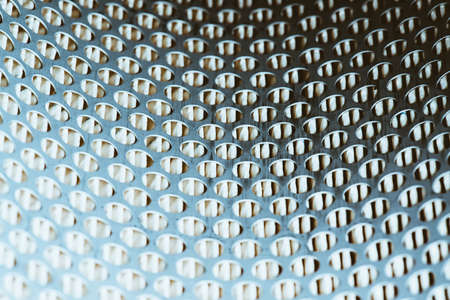Background of perforated metallic rounded wall close up. Macro photography of air filter with yellow paper.の写真素材