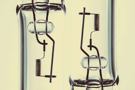 Detail image of filament from dipped beam bulb close-up with copy space on yellow background.